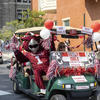 Hooter the Owl smiling and waving while riding a golf cart during the university's parade on Main Campus